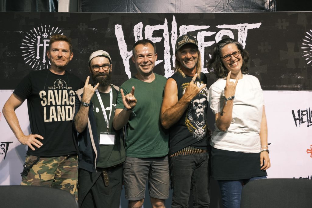 5 représentants associatifs posent au Hellfest en faisant le signe des cornes avec un grand sourire