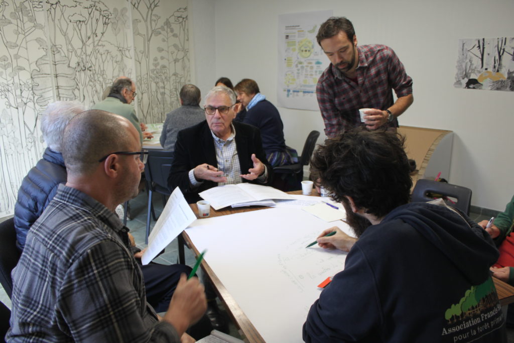 Plusieurs personnes discutent autour de documents posés sur une table